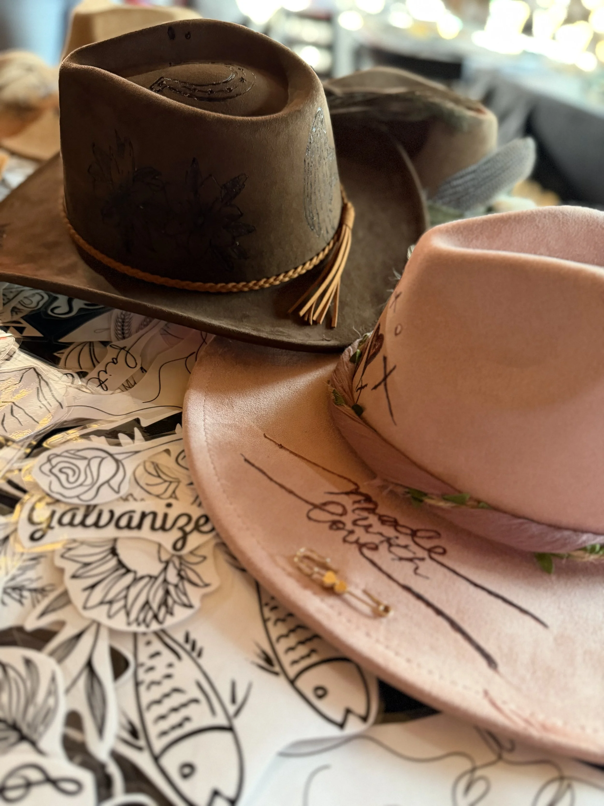 Close-up of a cowboy hat with floral designs, placed on a table with black and white decorative paper underneath.