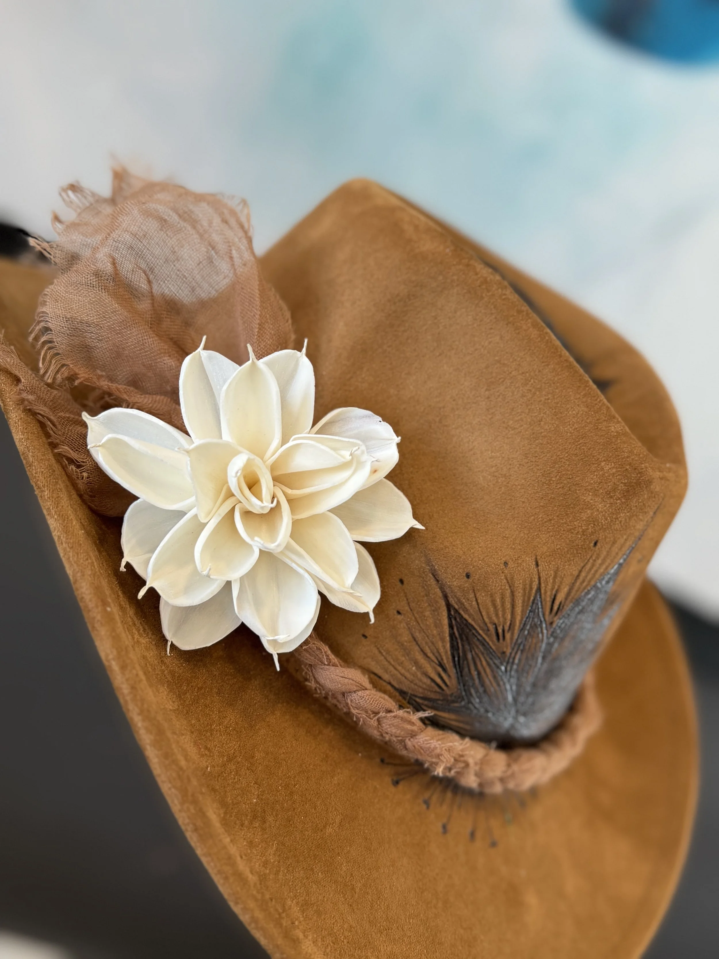 Close-up of a white flower and brown fabric wrapped around a gift box.