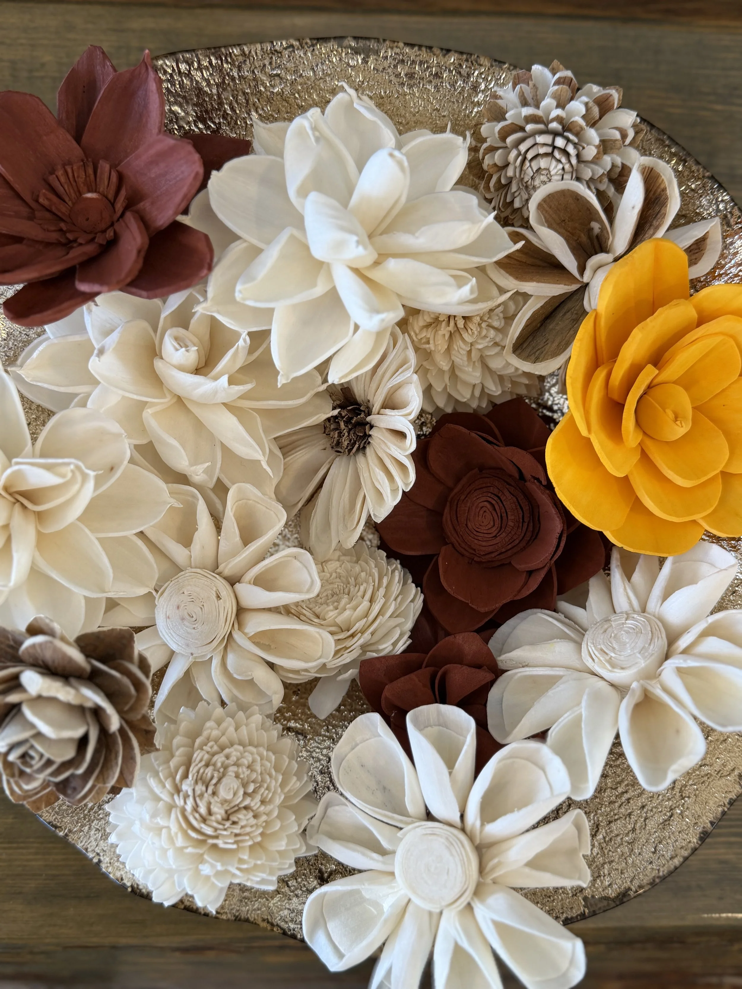 Arrangement of various cream, brown, and yellow paper flowers with a gold textured background.