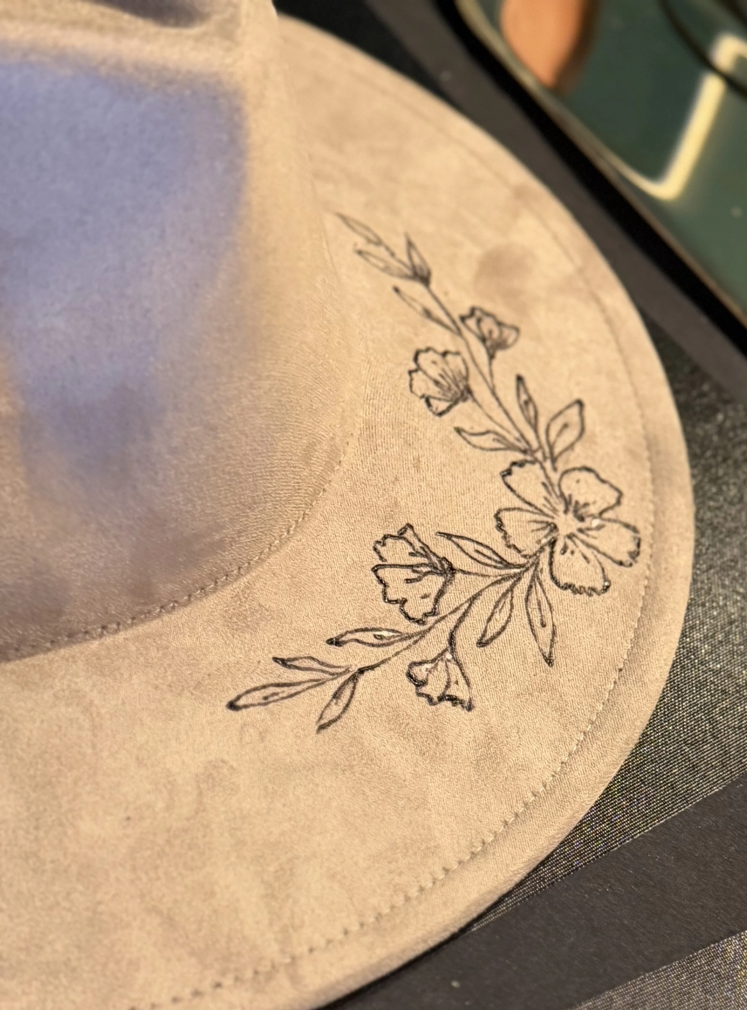 Close-up of a piece of beige fabric with a black floral design printed on it, placed on top of a black surface.