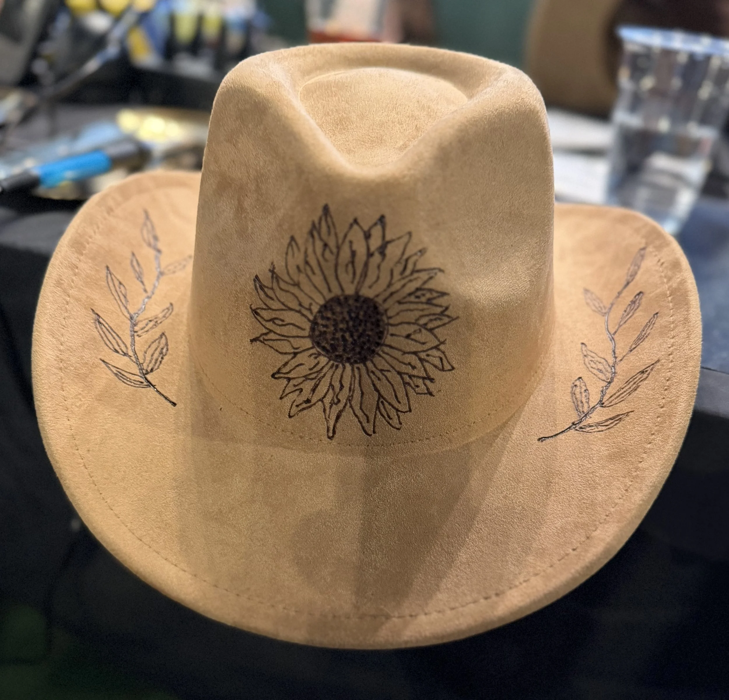 Close-up of a leather item with a sunflower design printed on it, with a blurred background.