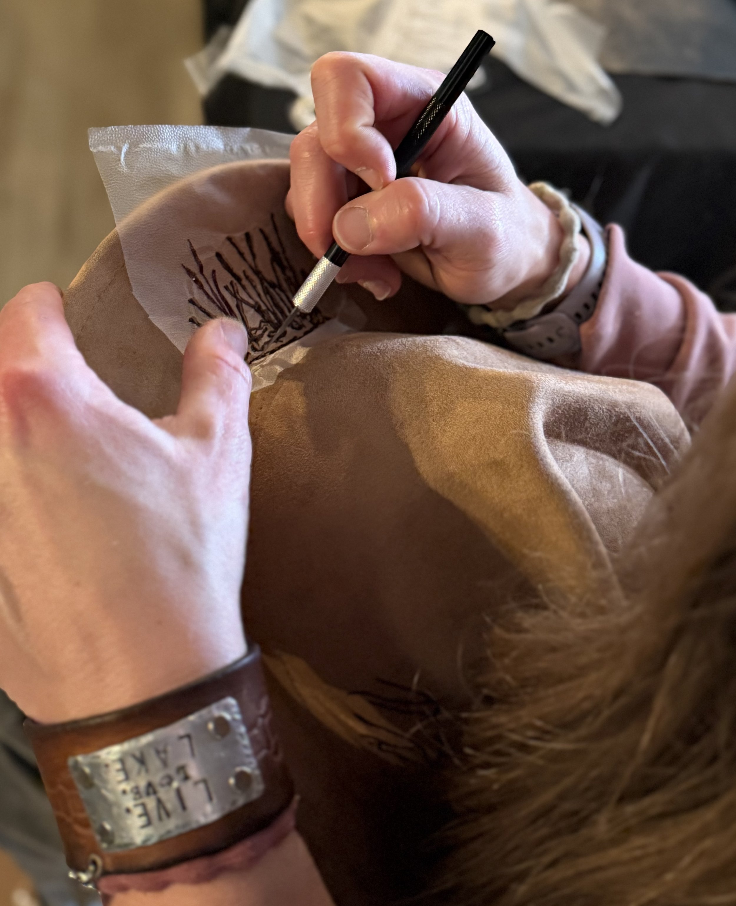 A person is tattooing a design on someone's skin using a tattoo machine.