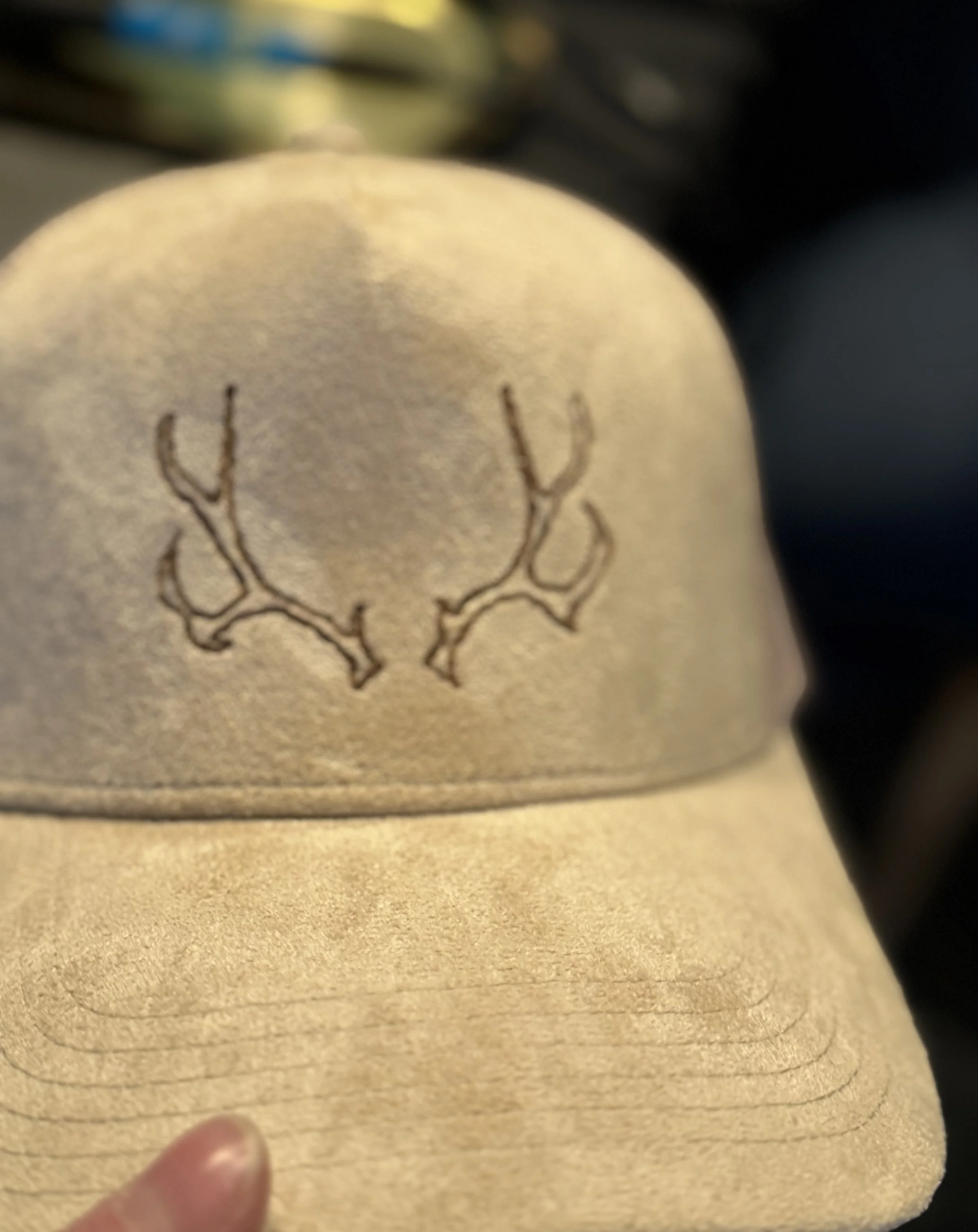 Close-up of a gold ring with etched design, being held by a person's finger.
