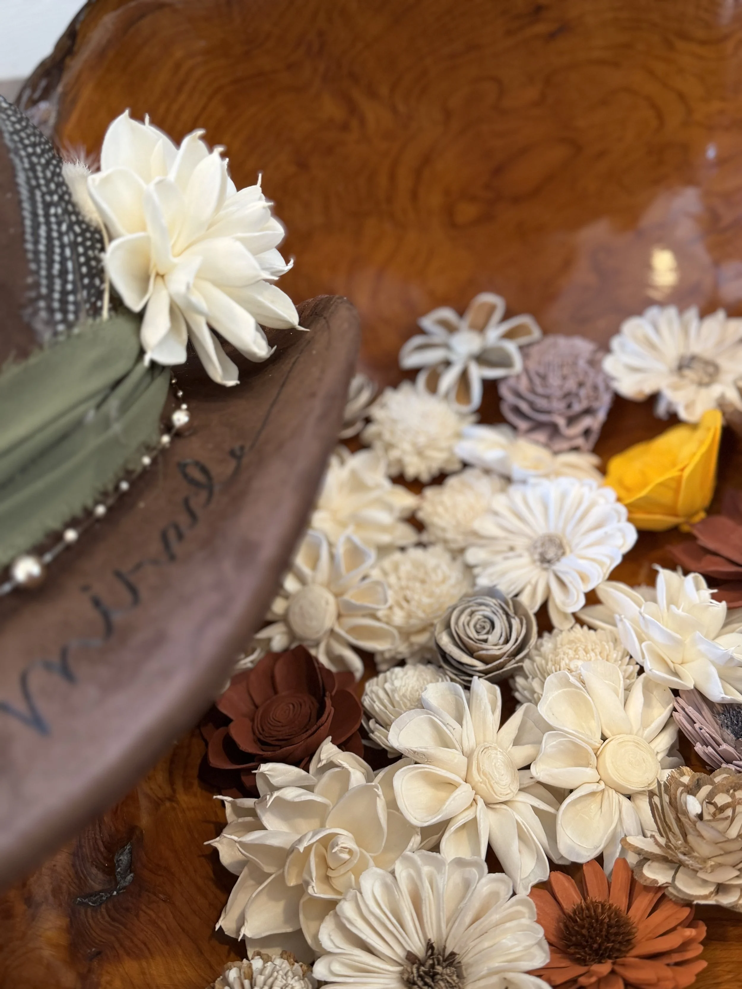 An assortment of cream, brown, and orange dried flowers and flowers arranged on a wooden surface.