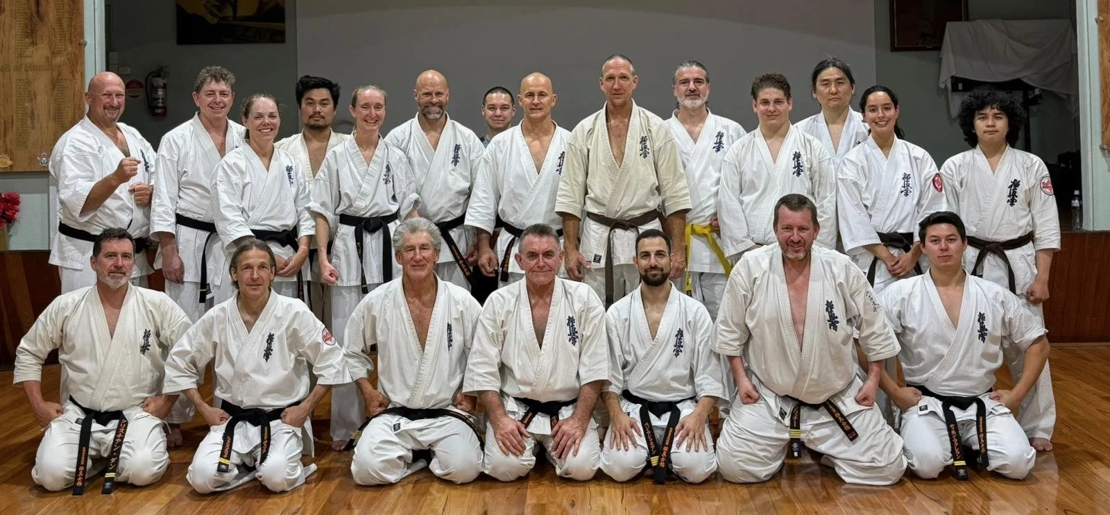 A group of martial artists in karate uniforms posing together indoors.