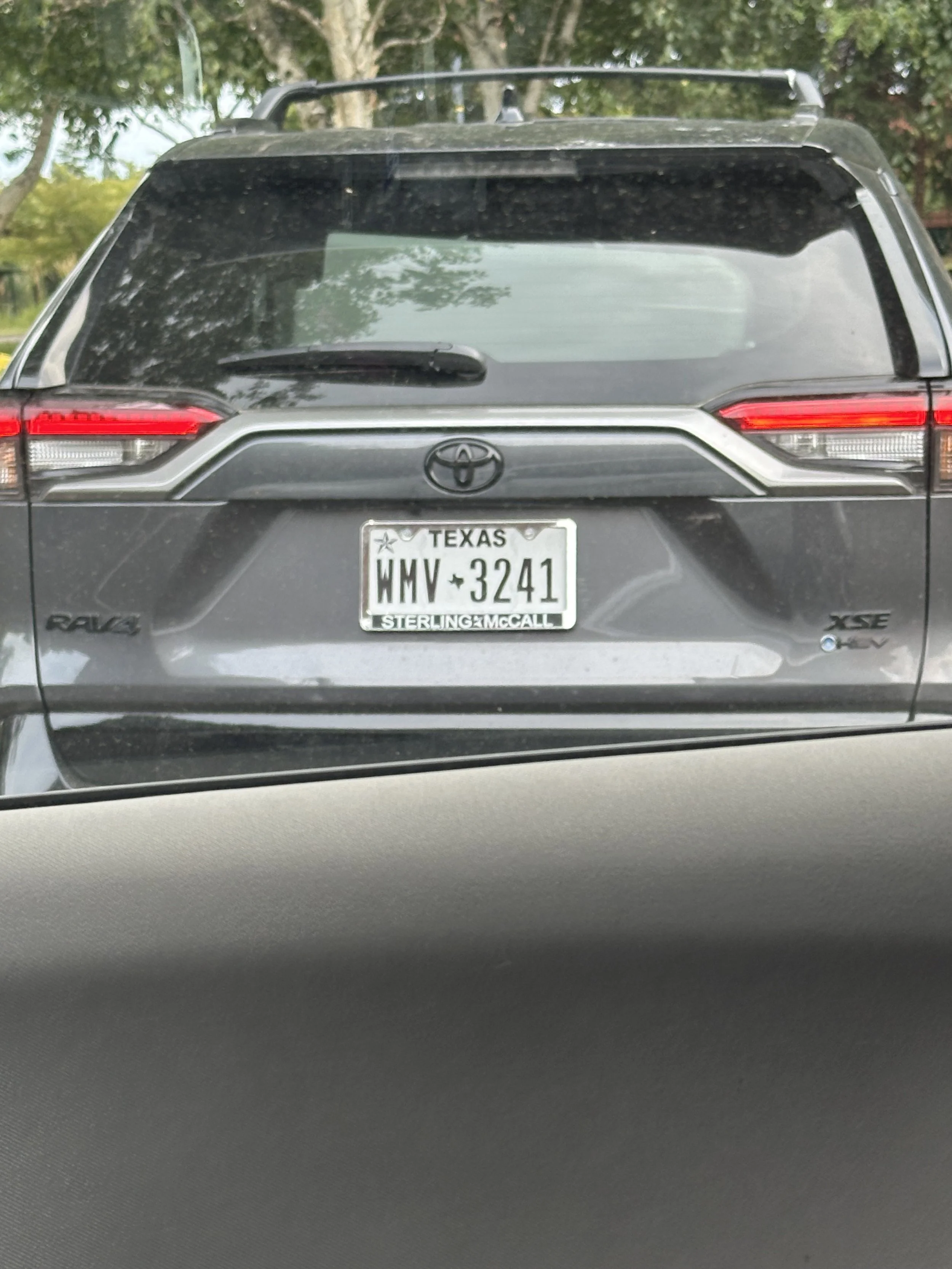 Rear view of a gray Toyota RAV4 with Texas license plate WMV 3241, featuring a black roof rack.