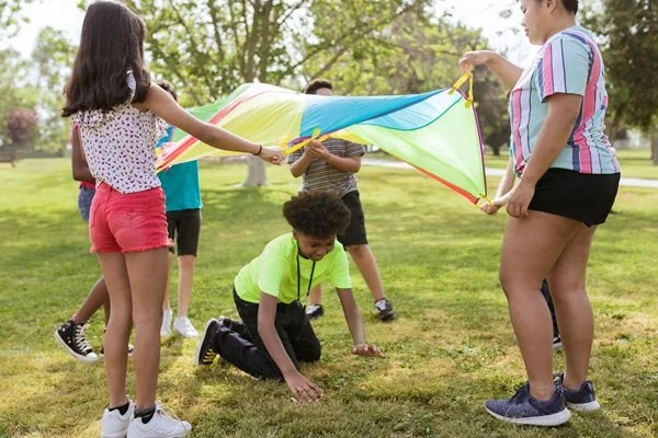 Kids playing with parachute at camp outside