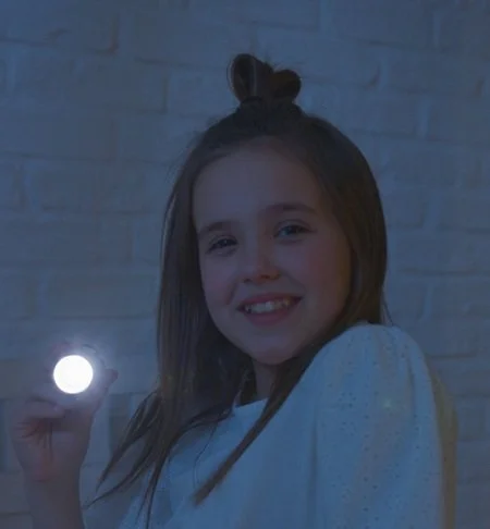 Girl holding flashlight at the camera