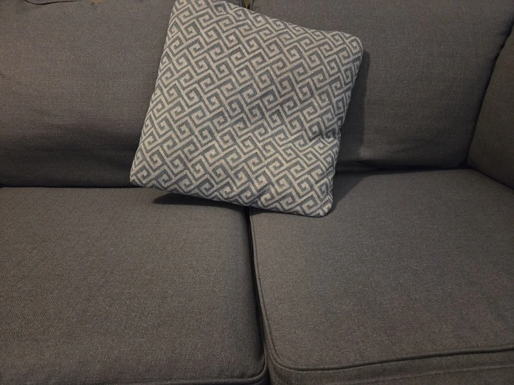 Our grey couch with a pillow in front