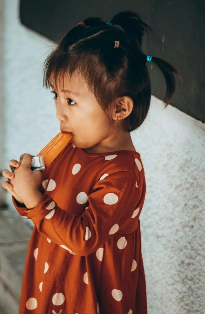 Little girl eating an orange popsicle