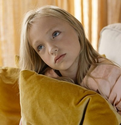 Girl looking bored holding yellow pillow