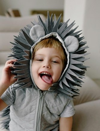 Child dressed up as a grey lion with his tongue out.