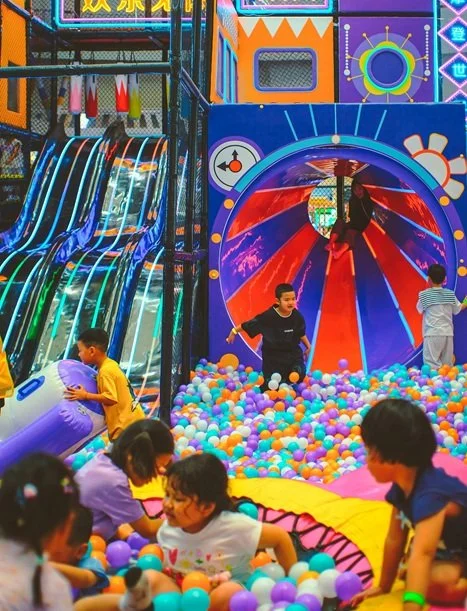 Chaotic indoor playground with bright lights and a ball pit