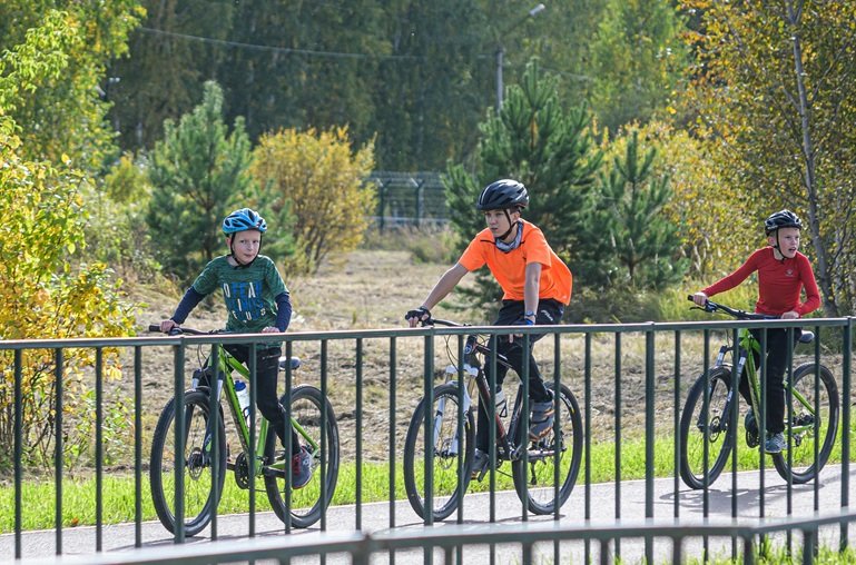 3 kids riding bikes on a greenway path
