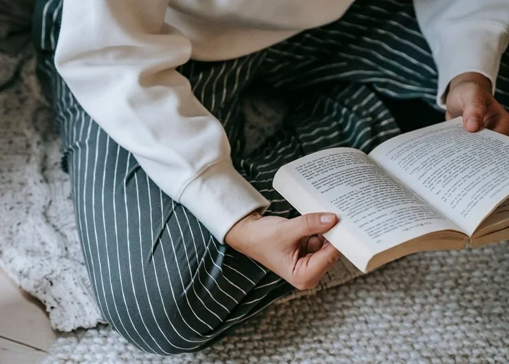 Person sitting on the floor reading a book