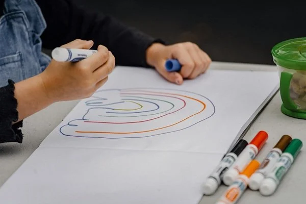Girl draws rainbow with markers