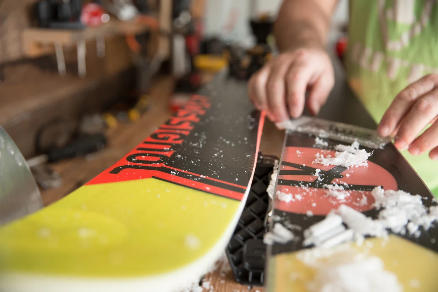 A person fixing a skateboard deck on a workbench, with tools and equipment in the background.