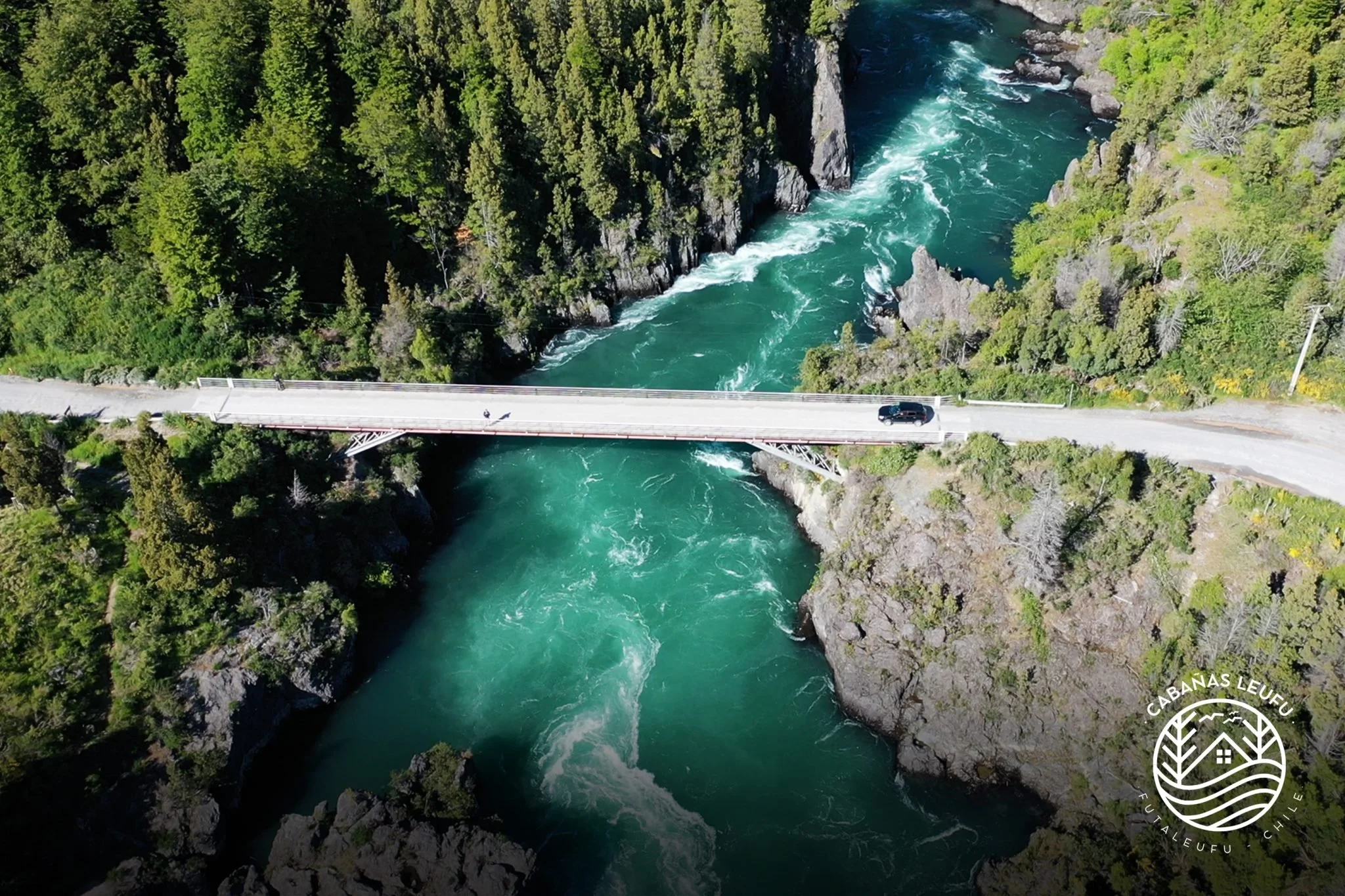 Puente sobre un río que atraviesa un cañón rodeado de vegetación verde.
