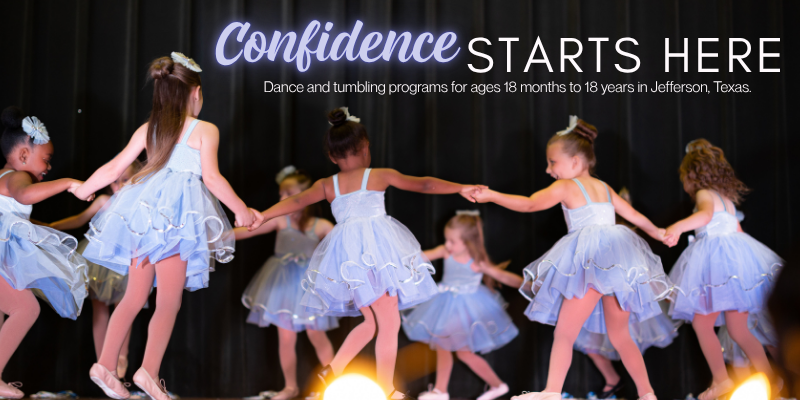 Young girls in light blue tutus and white tops dancing in a line on stage for a dance performance.