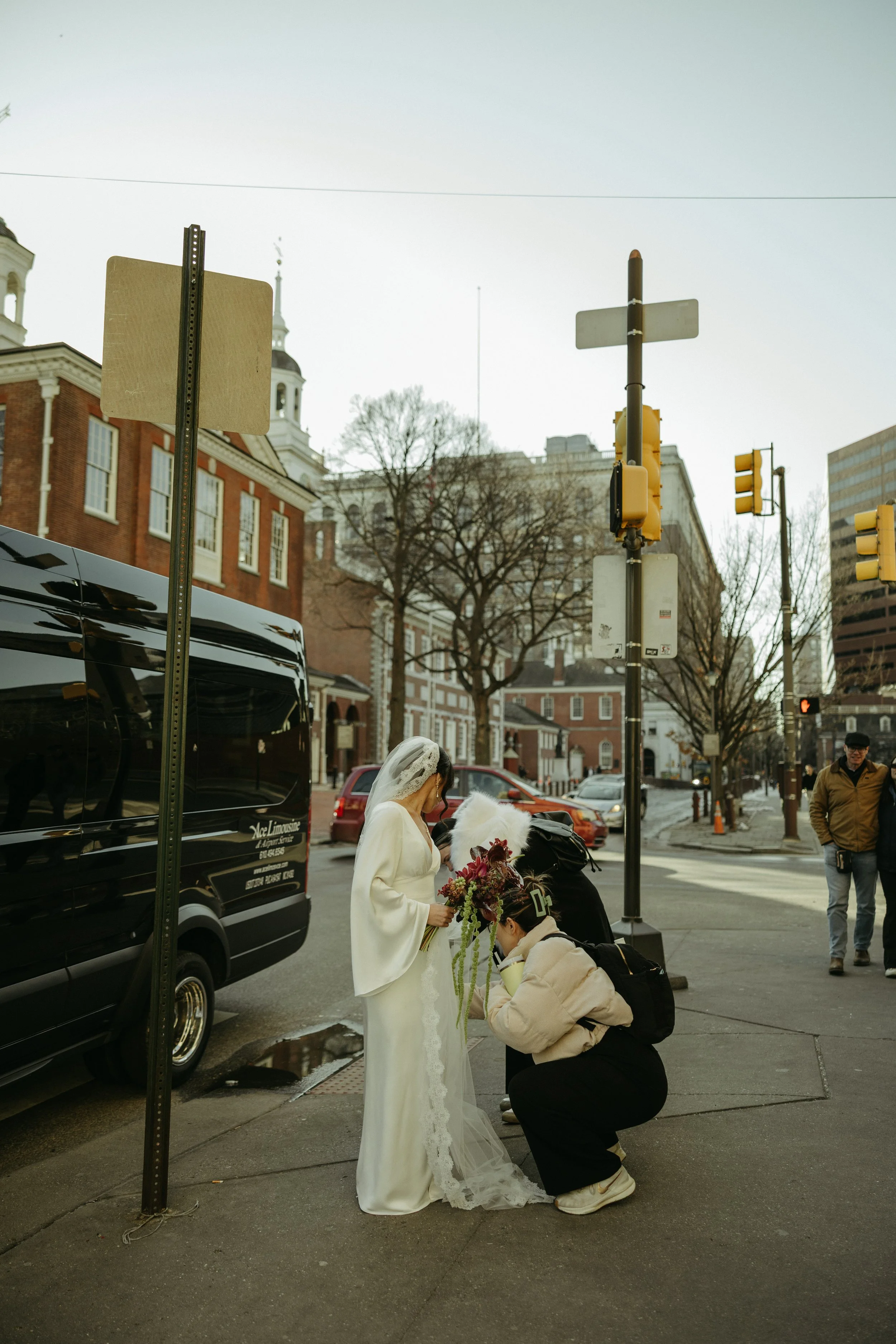 Philadelphia wedding content creator helping bride on a city street before ceremony