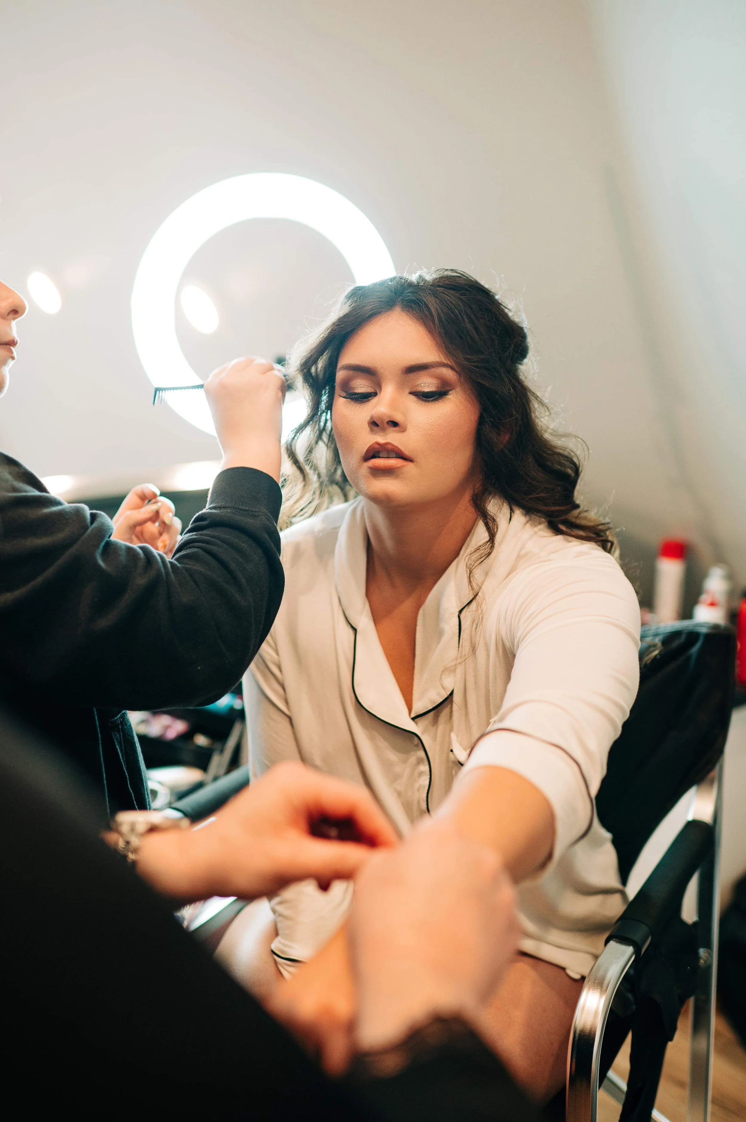 A woman getting her makeup done by a makeup artist in a well-lit room