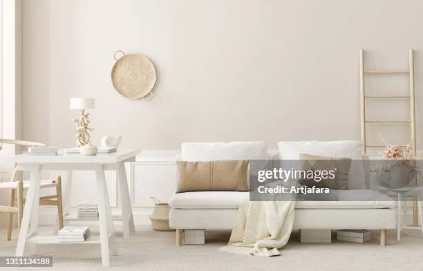 Living room with white couch, beige and gray pillows, white coffee table, and minimalist decor in neutral tones.