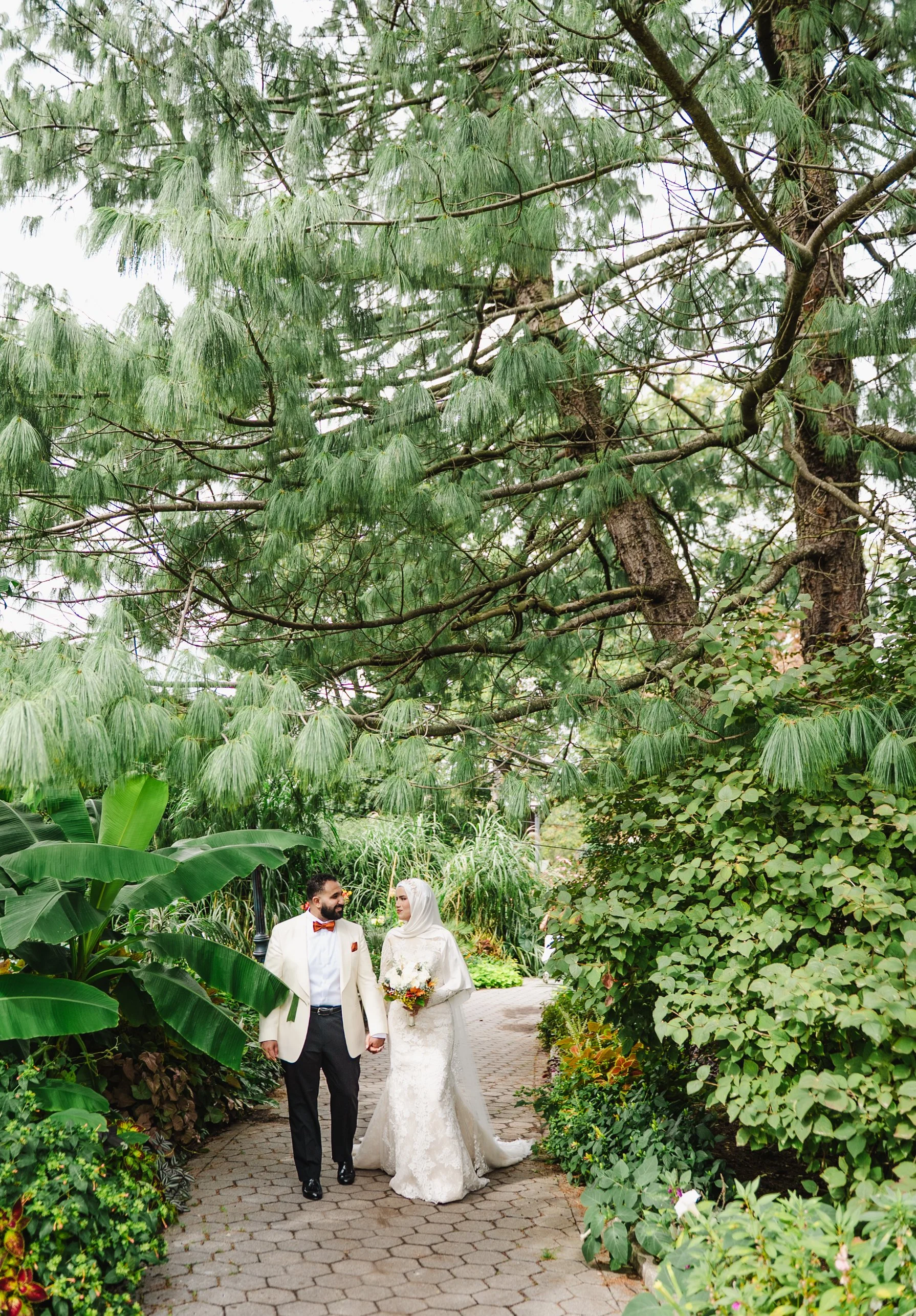 Laurie’s customers, Mariana and Carmen holding hands on a green lawn on their wedding day.