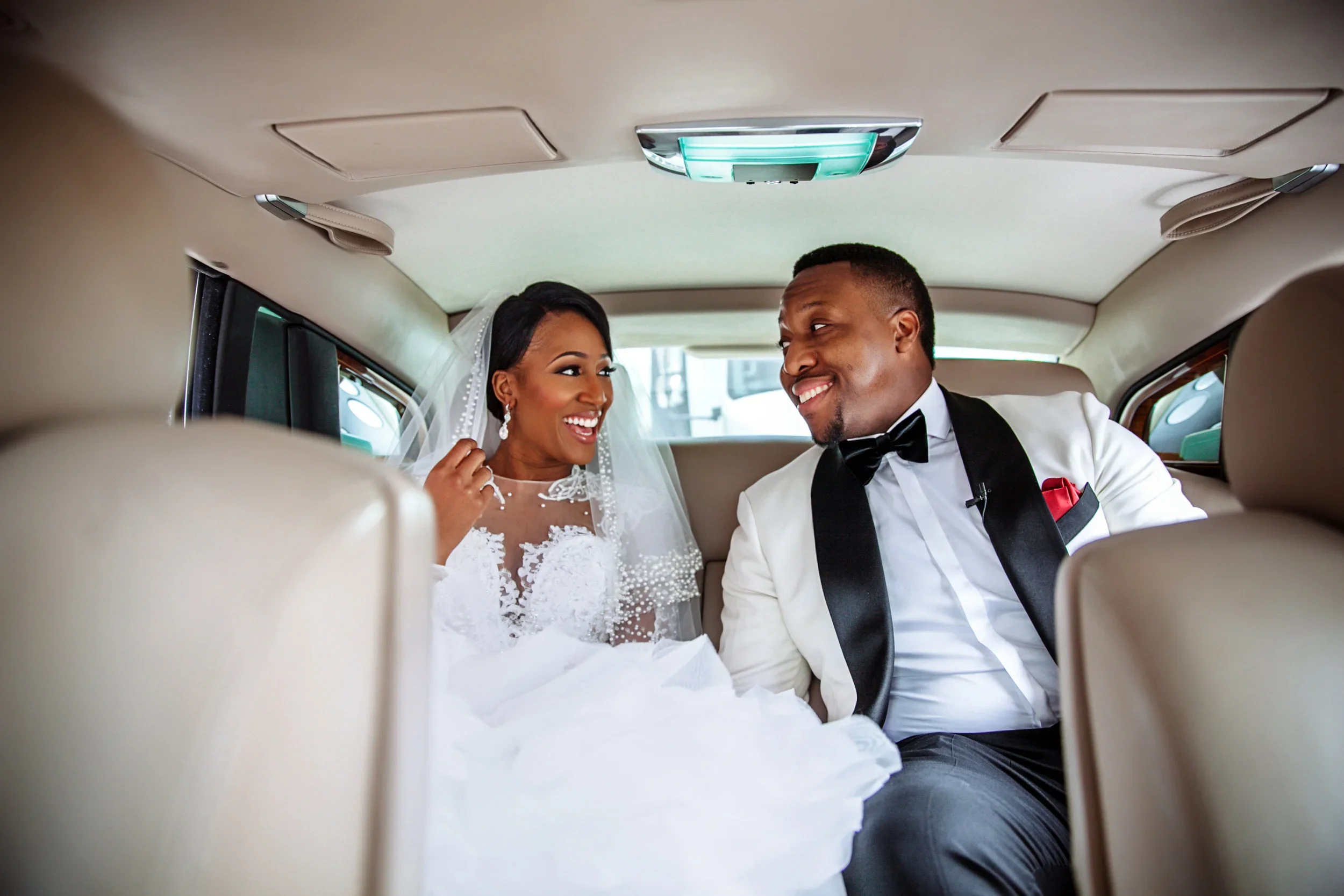 Happy bride and groom smiling inside a limousine after their wedding.