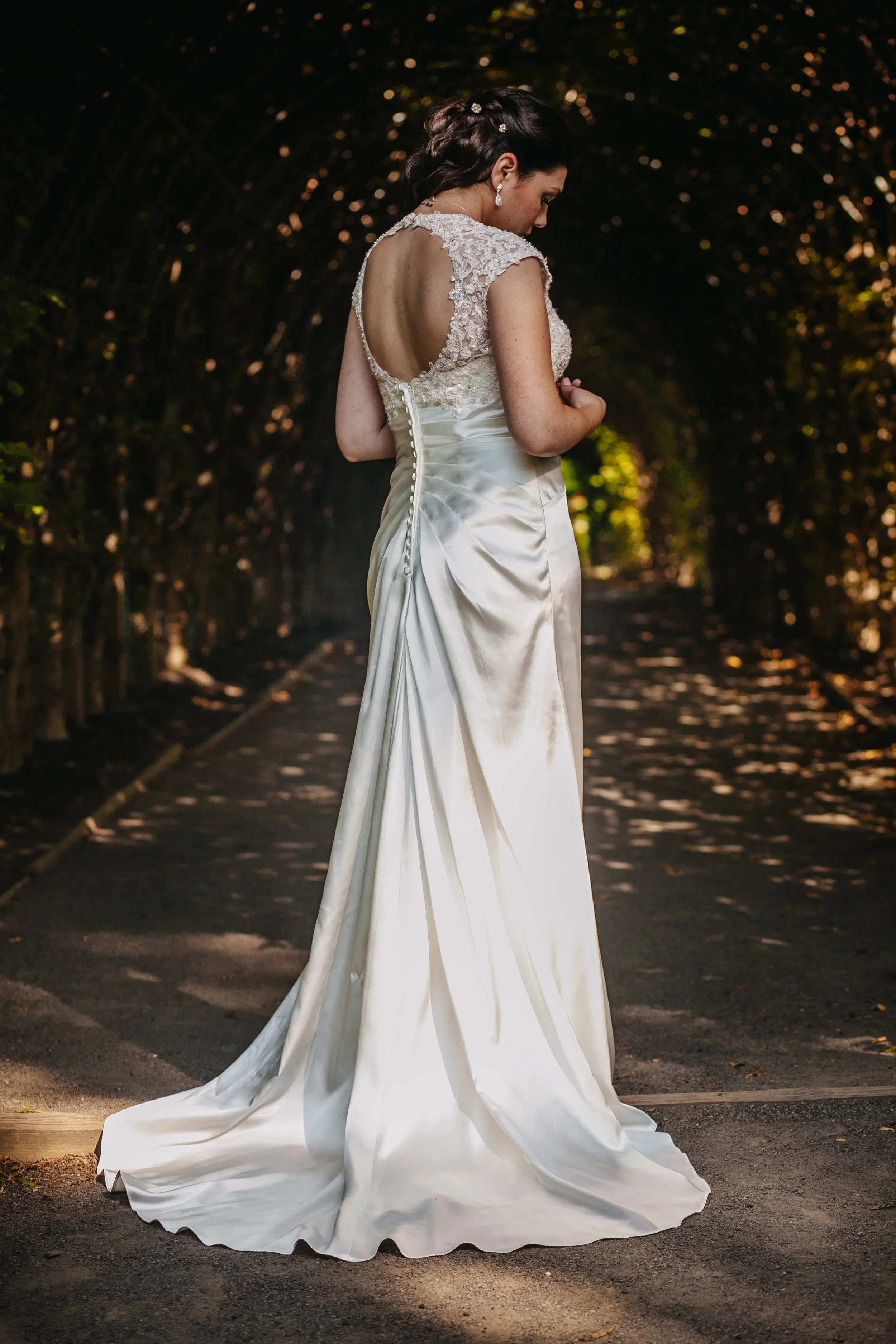 A rustic outdoor dining table decorated with a large leafy arrangement and red flowers in a brown bottle, set with plates, cutlery, and glassware for a meal.
