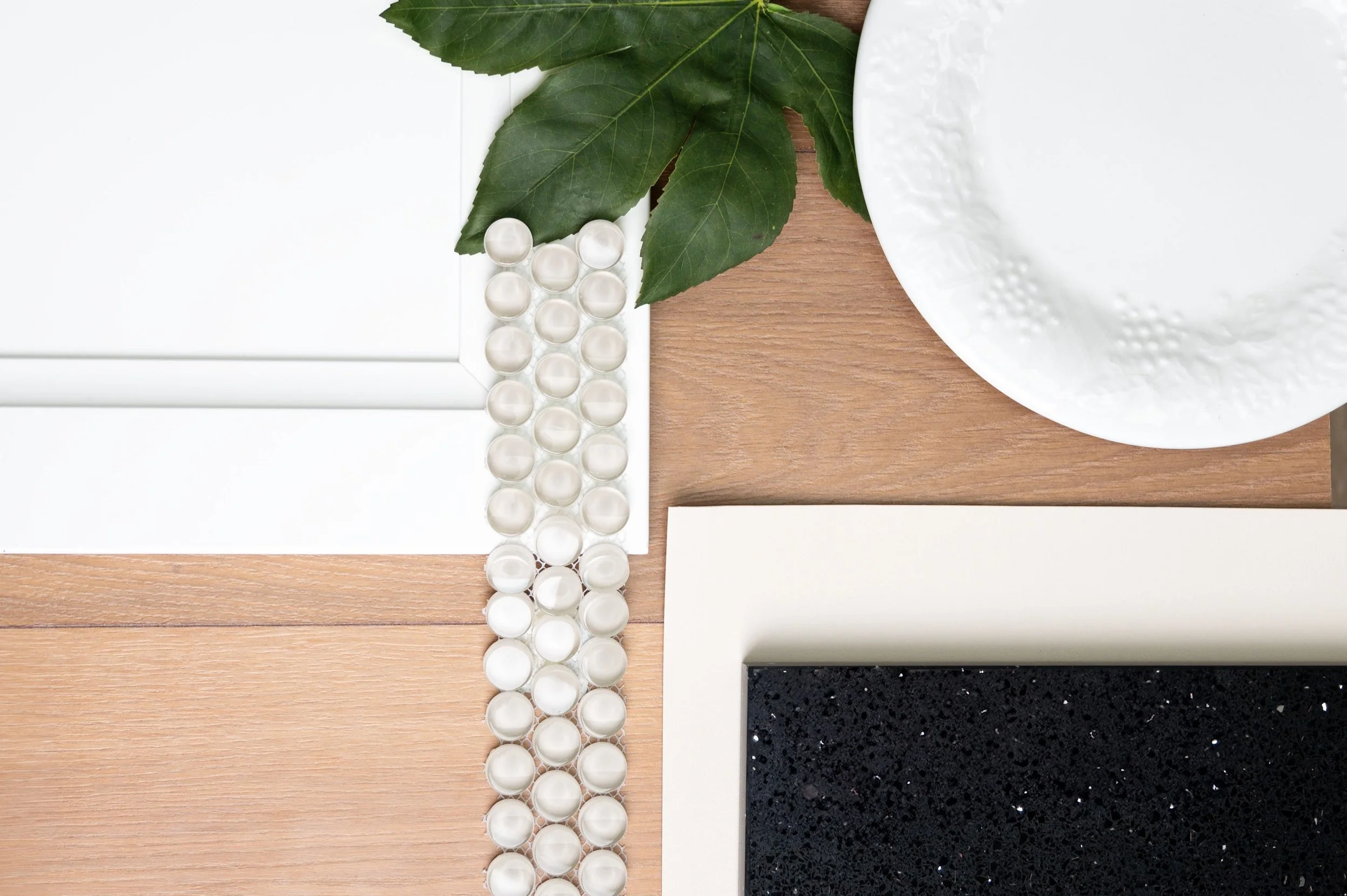 a flatlay palette is showing with a variety of hard home finishes, along with a leaf and a plate to pull the palette together