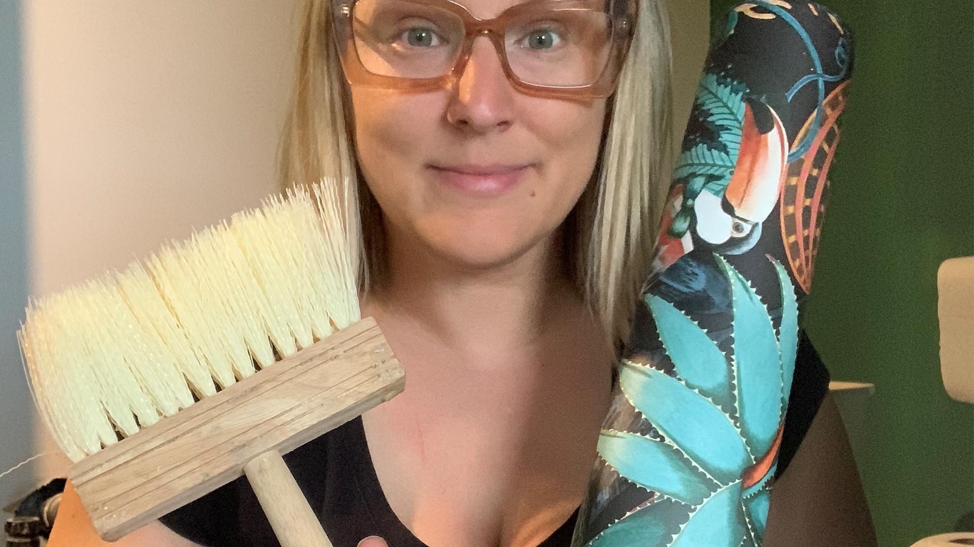 a girl poses for the camera with a roll of wallpaper and her wallpaper glue brush