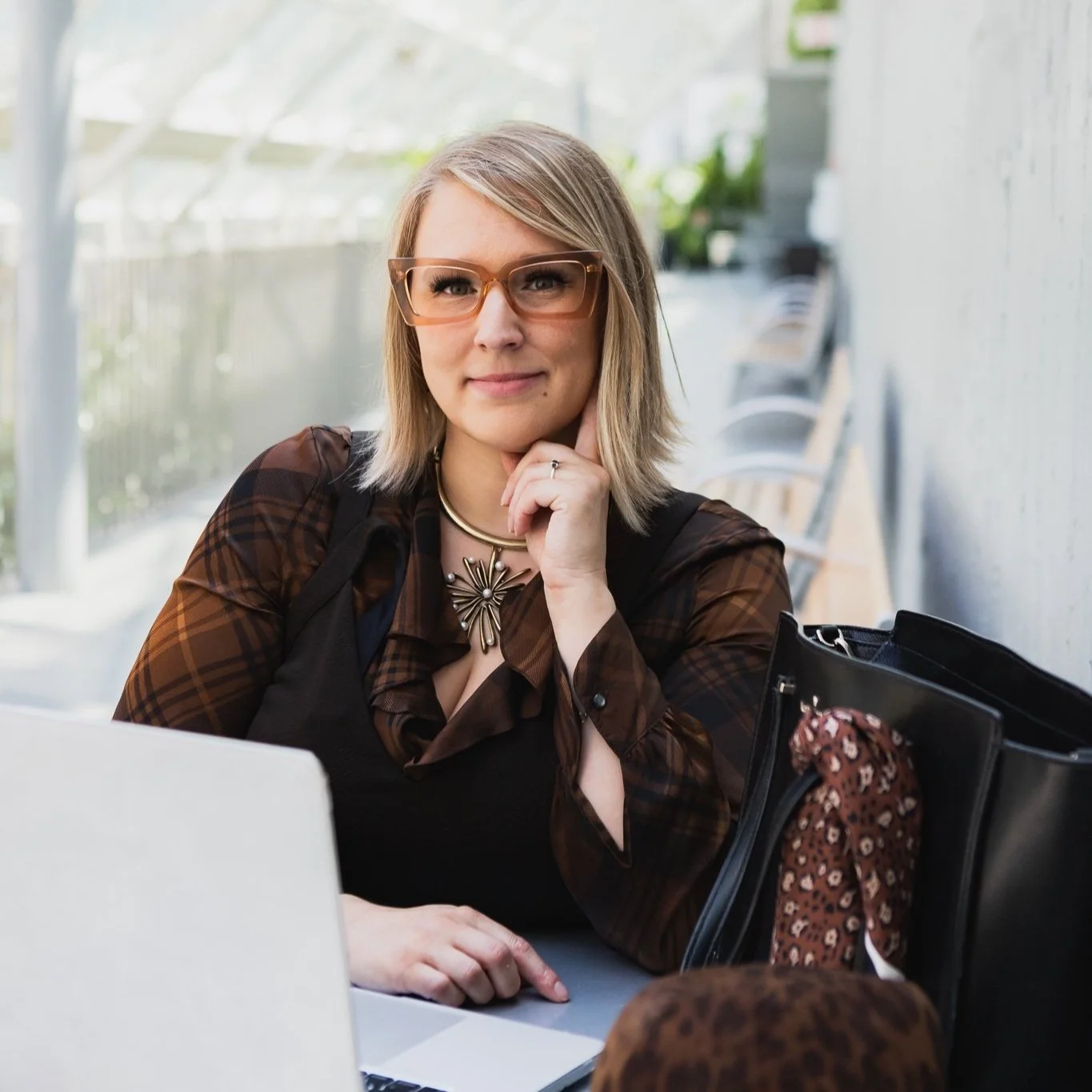 a girl with funky brown glasses and outfit sits in front of her computer ready to take on your design problems