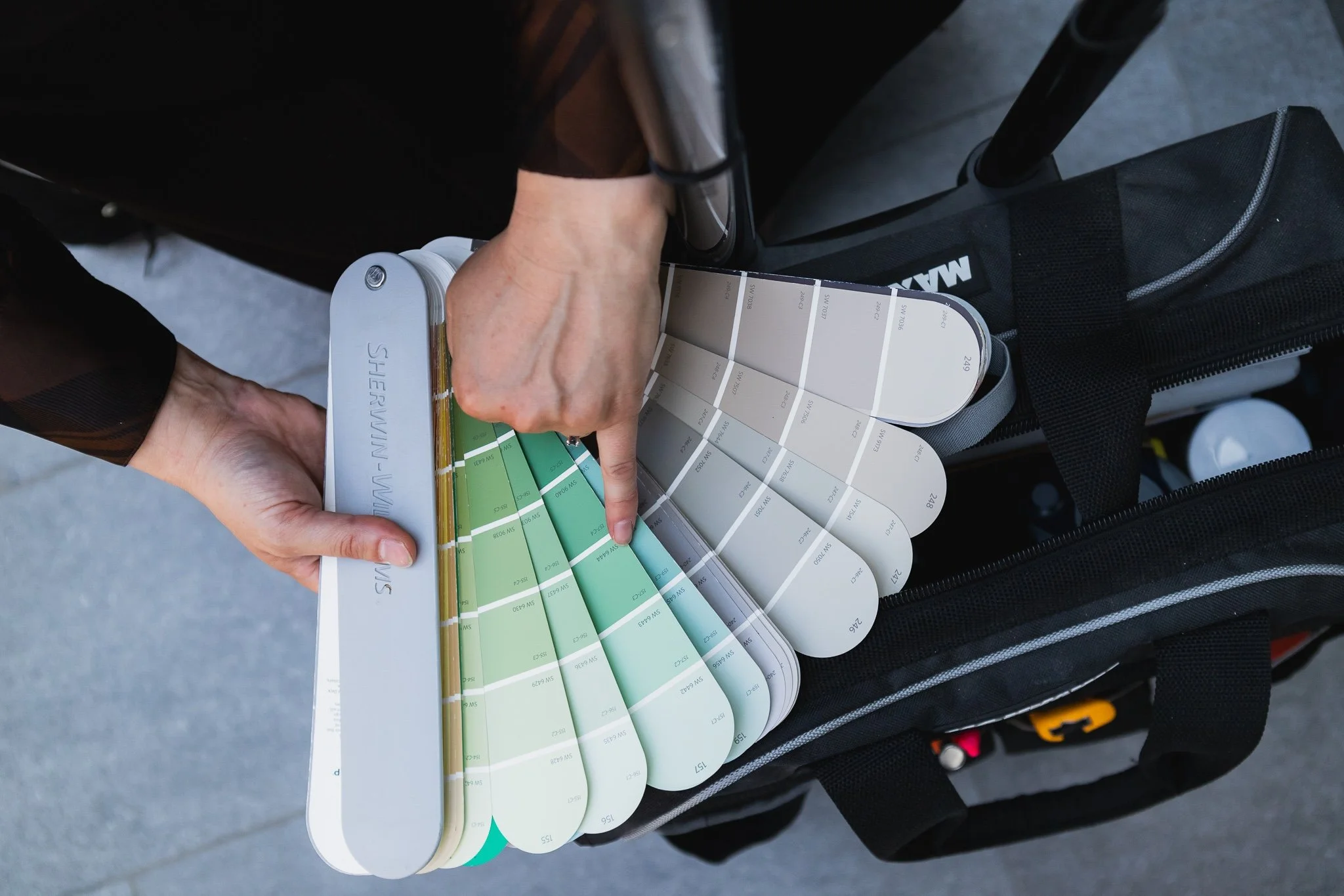 a paint color fan deck is shown with a paint color consultant pointing to a paint color option in the deck