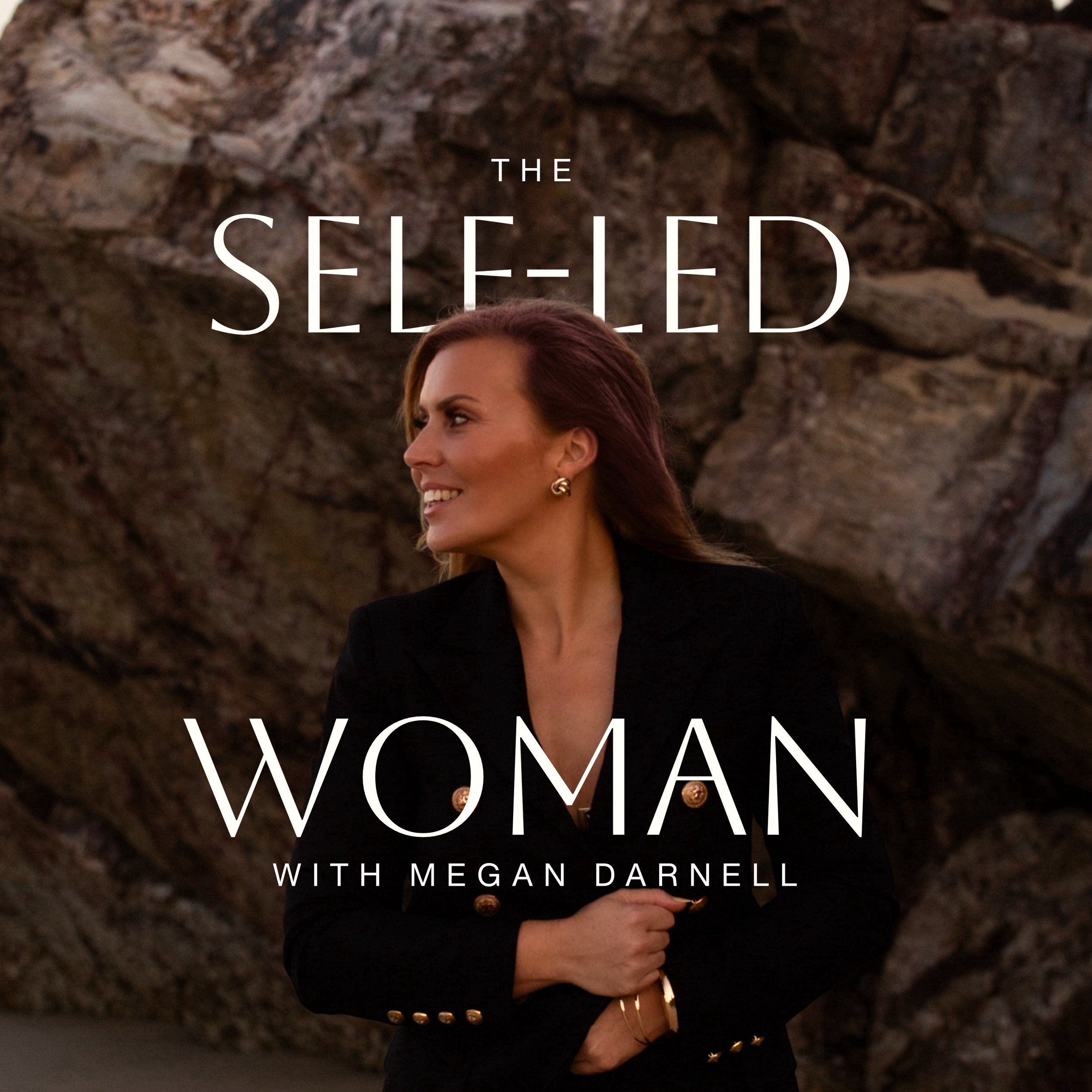 Podcast cover art featuring a woman with long, reddish-brown hair, wearing a black blazer with gold buttons, smiling and looking to her left, standing outdoors in front of large rocks. The text overlay reads 'The Self-Led Woman with Megan Darnell'.