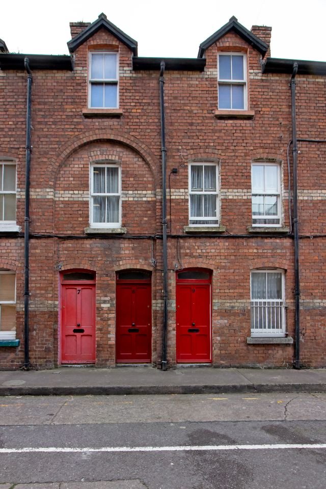 Three-storey red brick terraced houses with red doors.