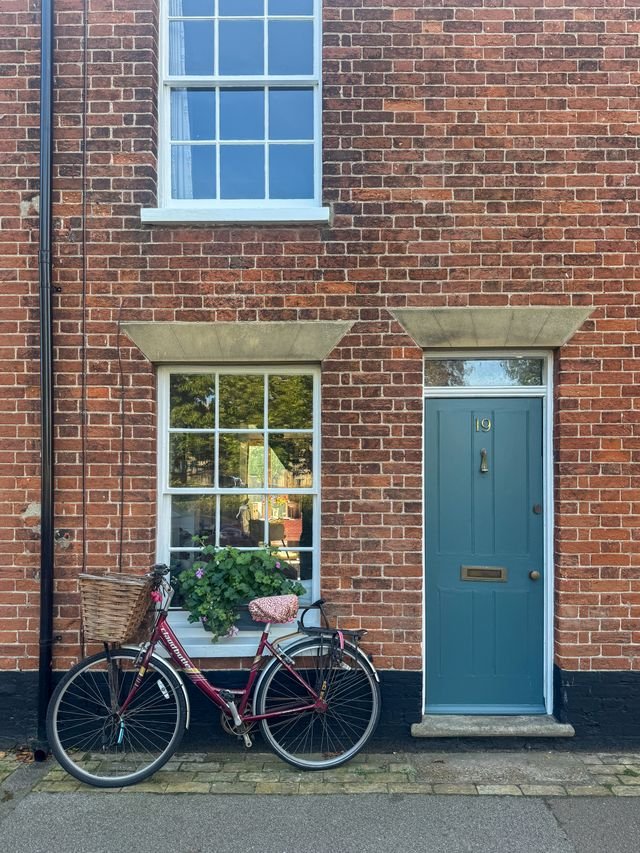 A Georgian brick house with sash windows, blue door and bicycle in Southwold, Suffolk.