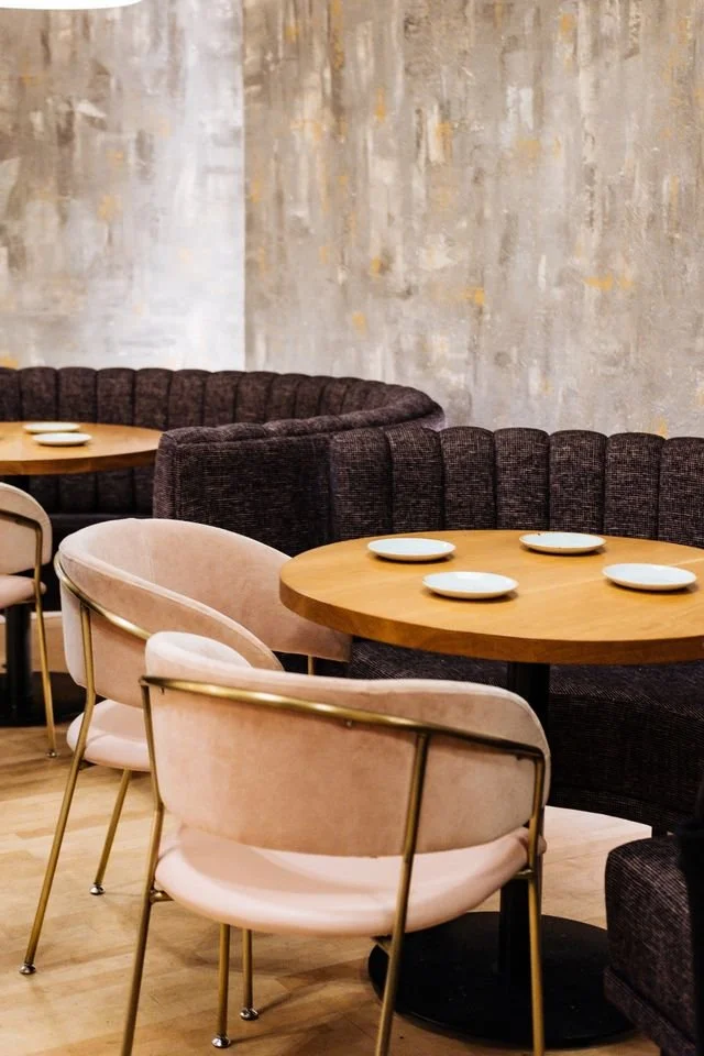 Interior of a modern restaurant with round wooden tables and residential flats above.