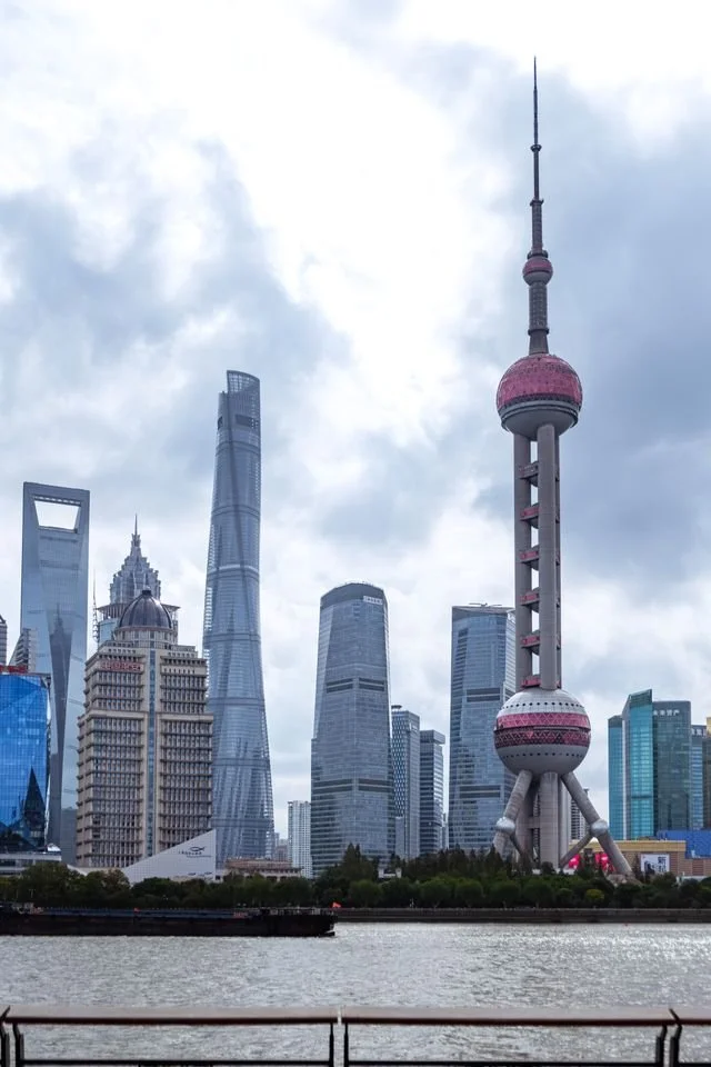 The Lujiazui skyline in Pudong, Shanghai, China in front of cloudy sky.