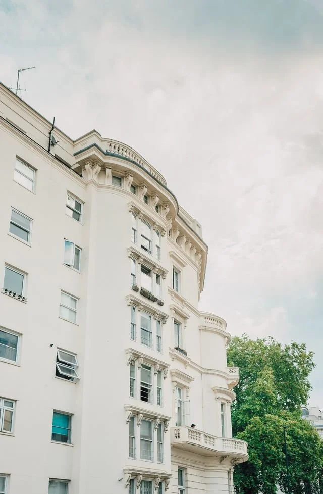 Modern London apartment exterior with white walls and cloudy sky.