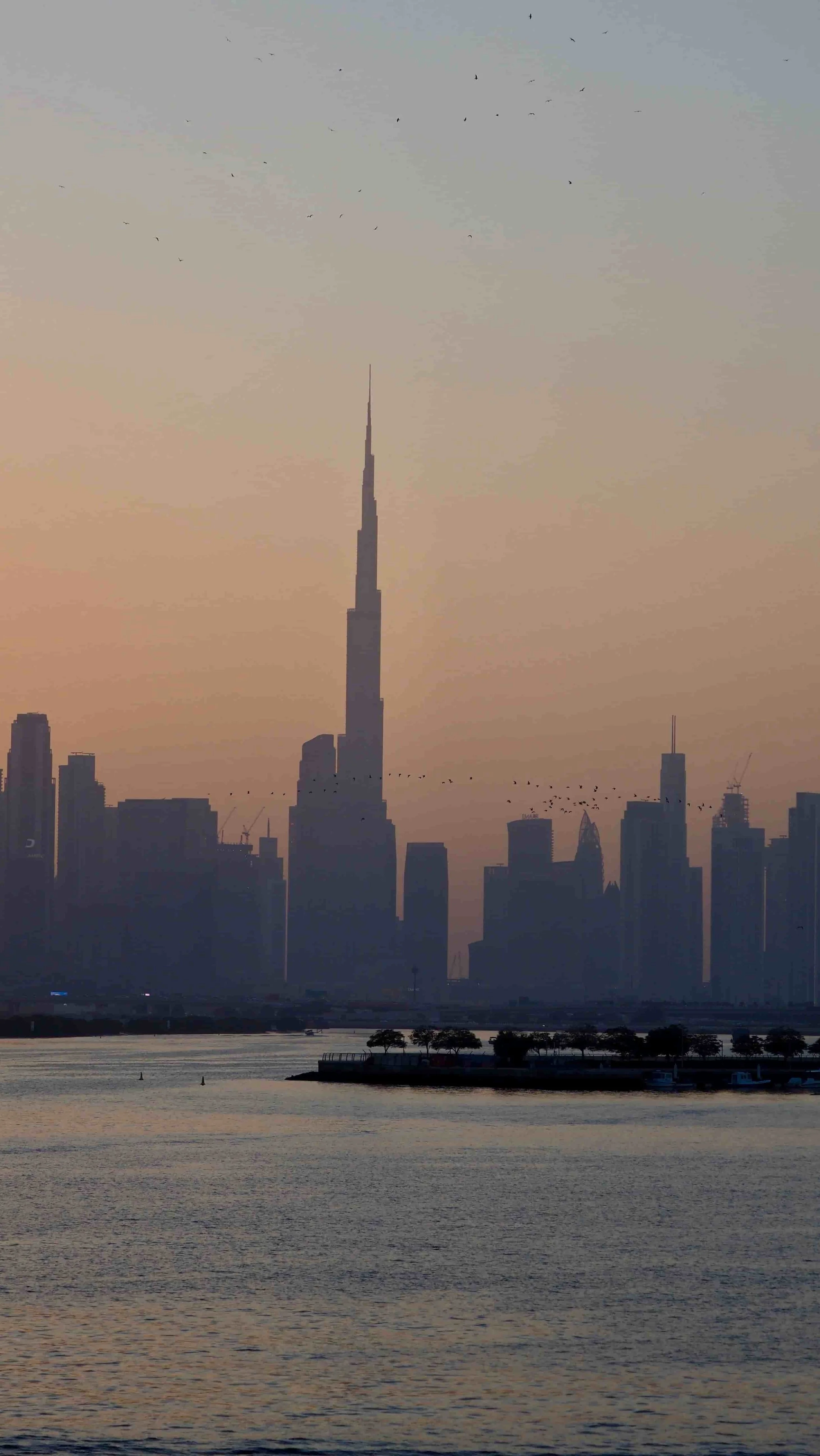 Silhouette of downtown Dubai skyline with Burj Khalifa at sunset.