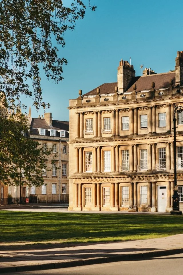 A high value heritage house with sash windows and chimneys, overlooking a green and trees.