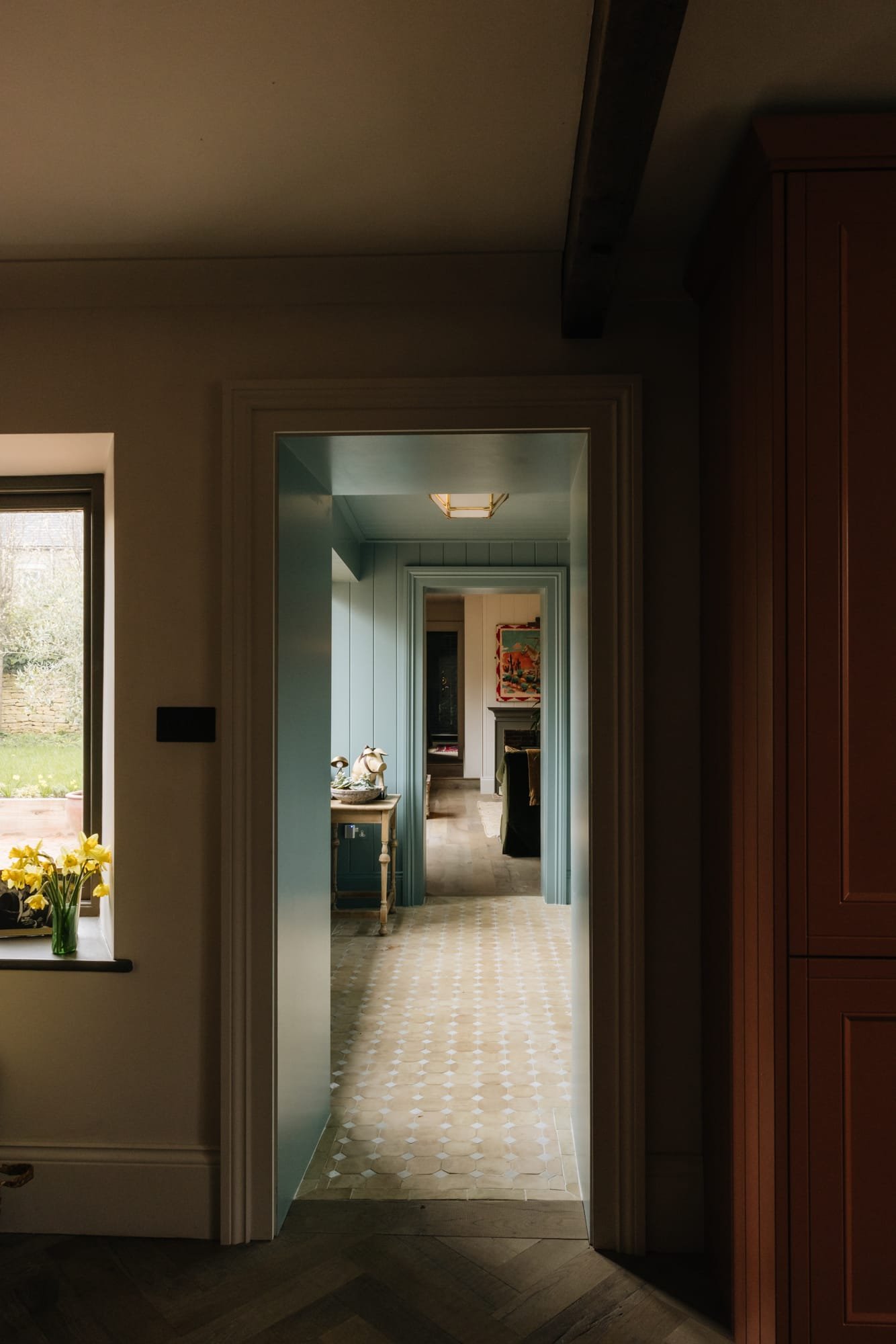 Multiple doorways leading to different rooms in a house, with a hallway and various furnishings, including a window with yellow flowers.