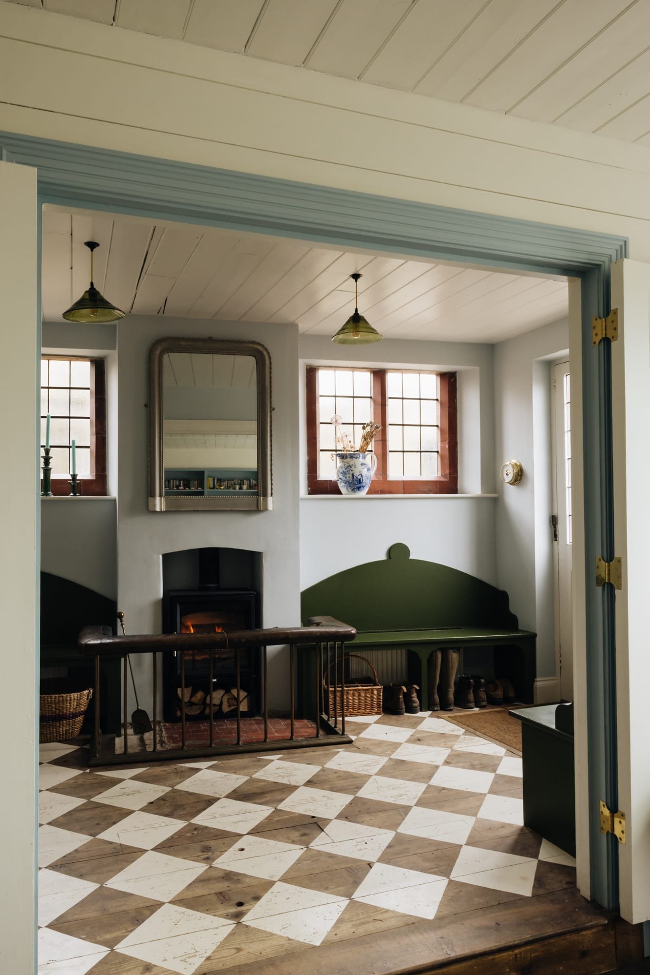 Interior view of a cozy room with a fireplace, mirrors, and vintage decor, visible through a blue doorway with gold hinges.