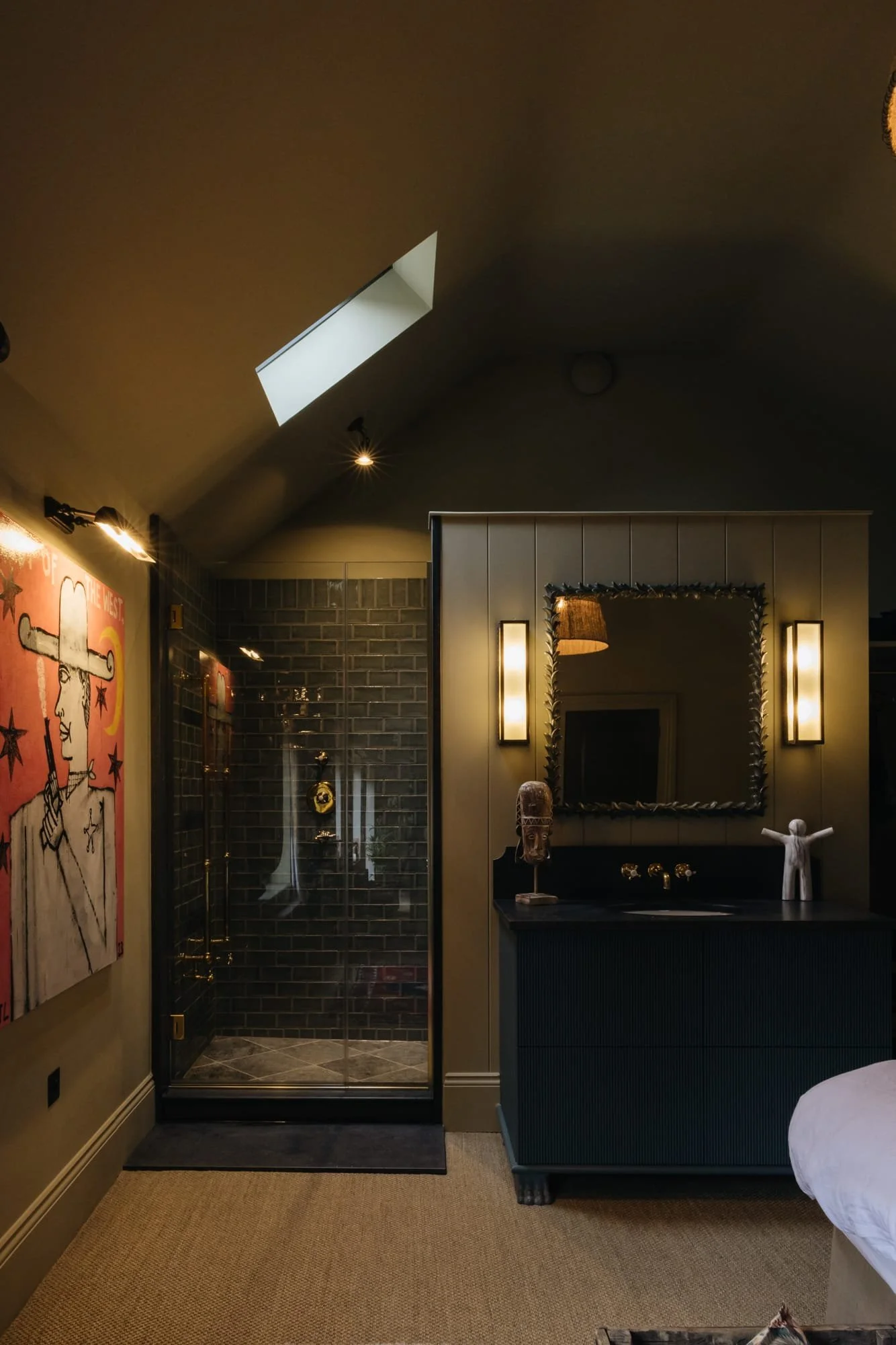 Interior view of a room with a glass shower enclosure, wall art, a mirror, and decorative sculptures.