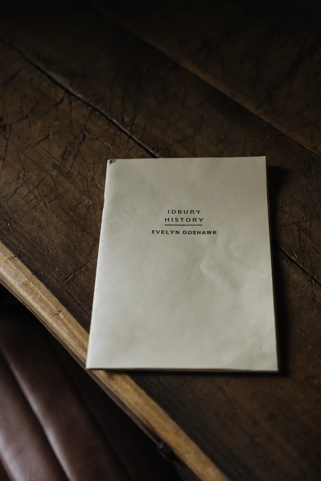 Book titled 'Idbury History' by Evelyn Goshawk placed on a wooden surface.