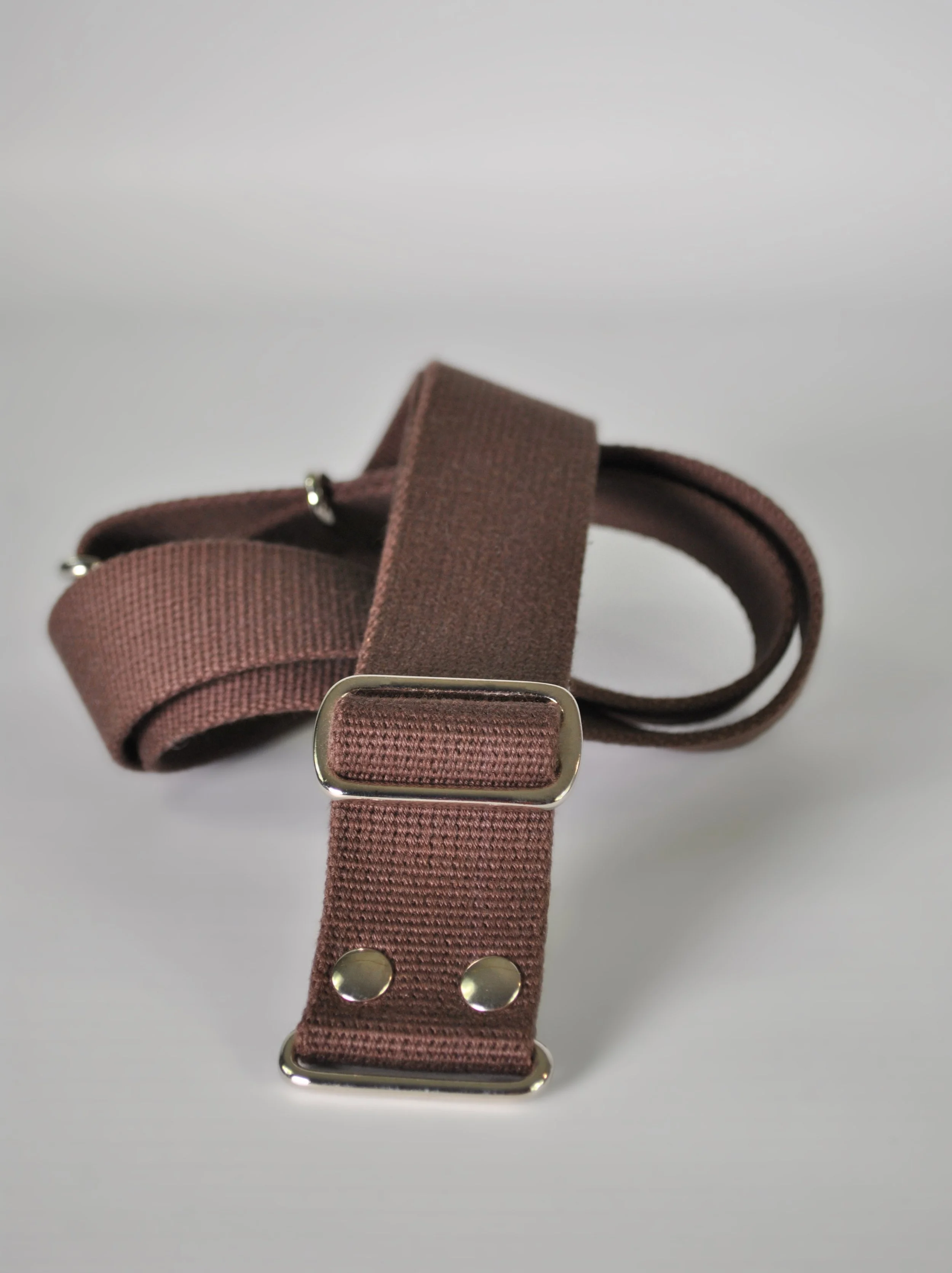 A brown adjustable cotton straps with silver metal hardware on a plain white background.