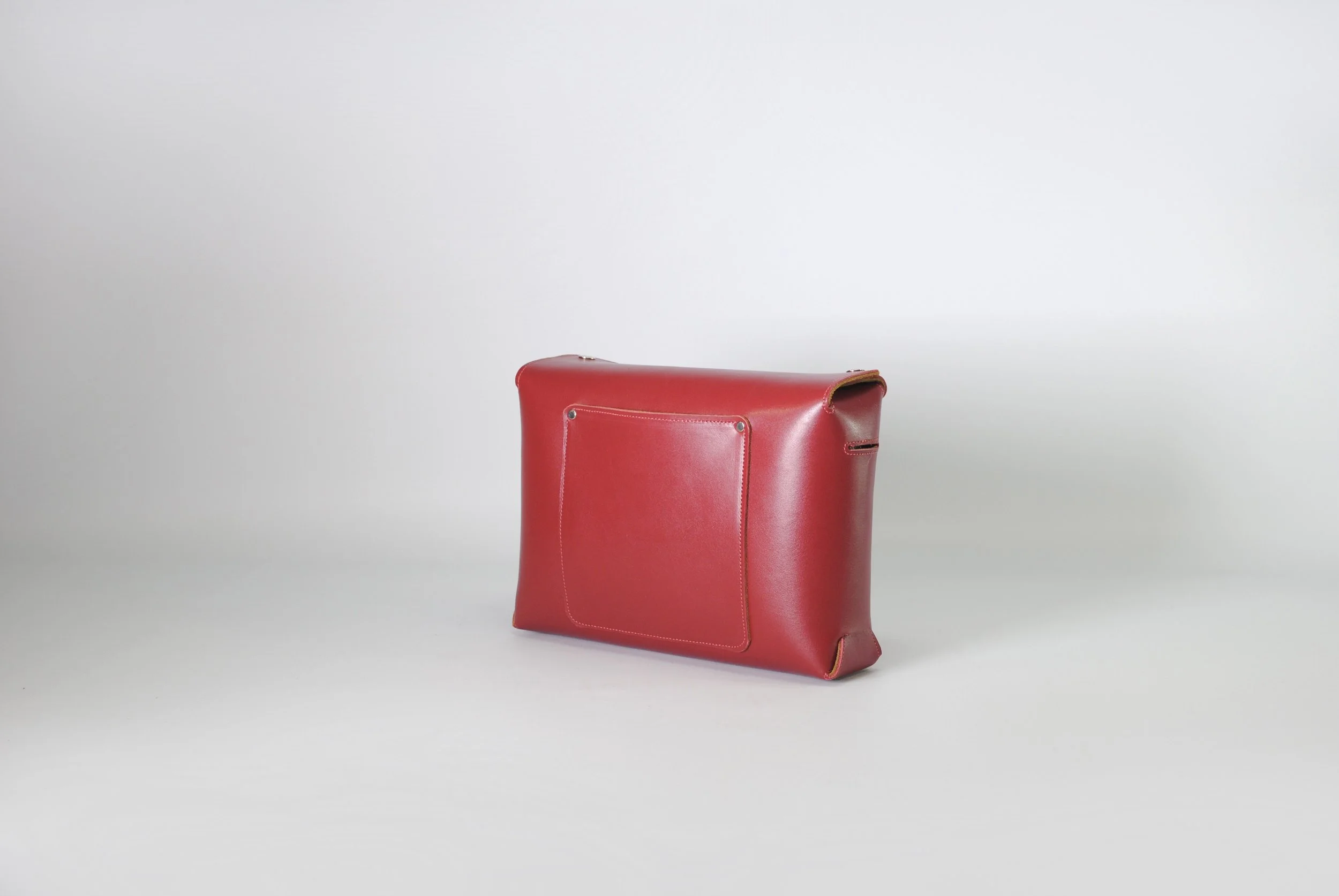 Red leather bag with a front pocket, positioned on a plain neutral background.