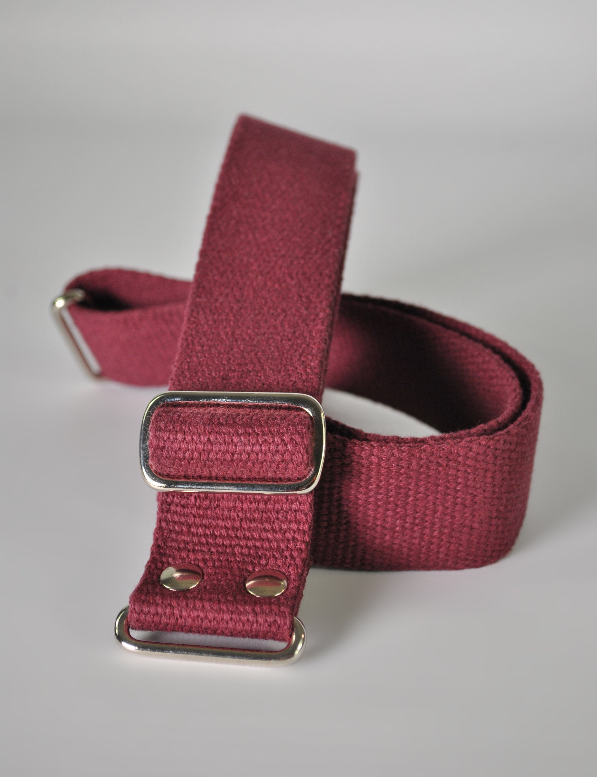 A maroon-colored fabric strap with metal sliders and loops, likely a luggage or bag strap, on a light background.