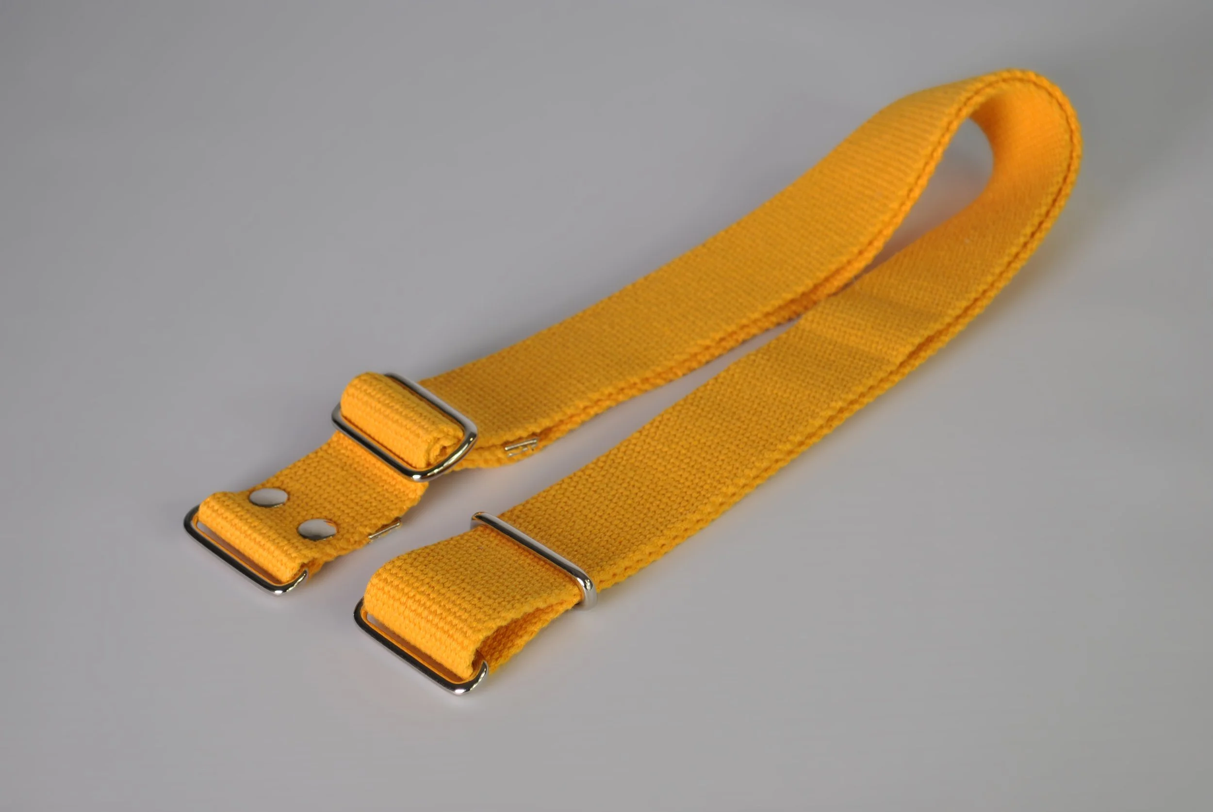 Yellow adjustable polyester strap with metal buckles on a light gray background.