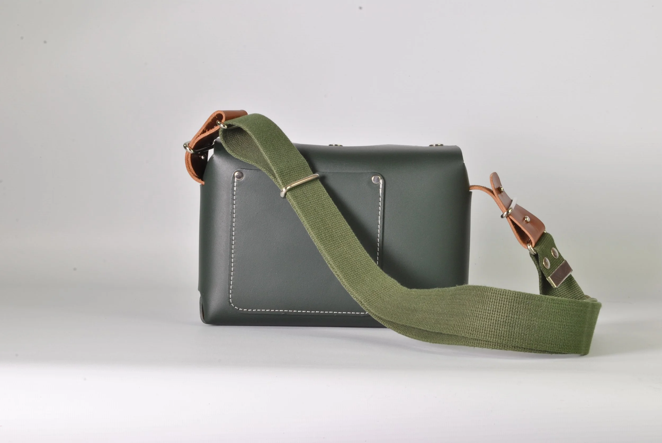 Gray leather crossbody bag with green strap and brown accents on a plain white background.